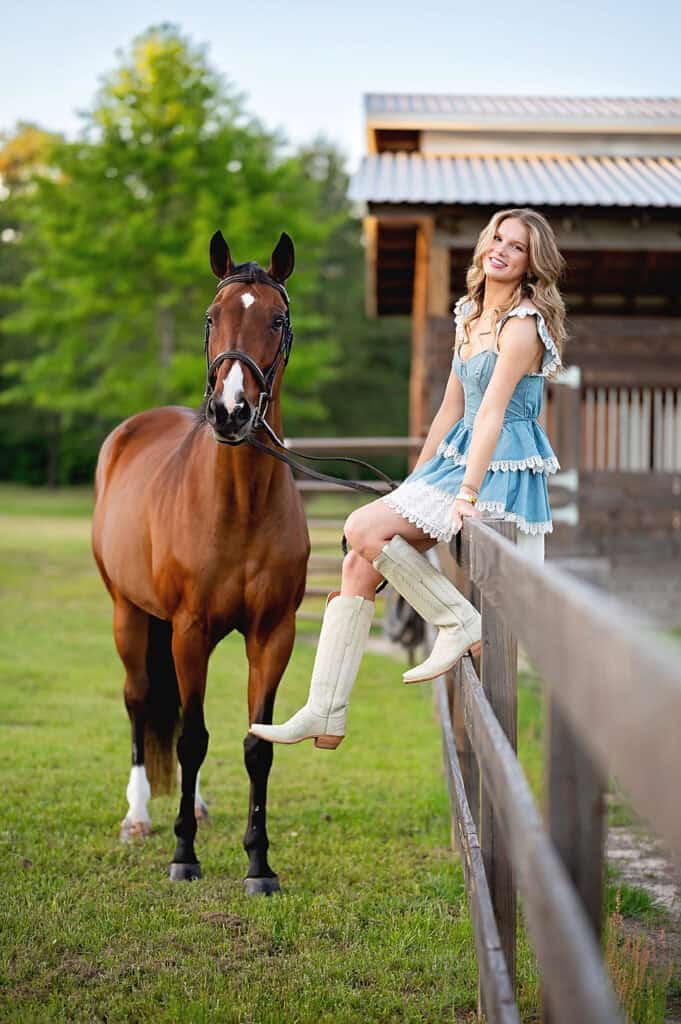 senior girl by a barn with a horse.